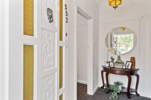a hallway with a door and a table with a mirror at East Hills Waterfront Bliss in East Hills