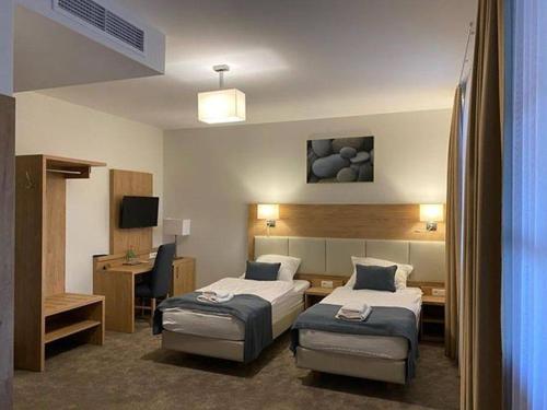 a hotel room with two beds and a desk at Hotel i Gospoda Pod Kamieniem in Lipnica Murowana