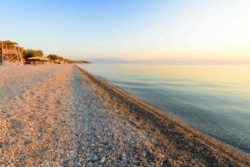 a pebble beach next to a body of water at Seaside Akrata's House in Paralía Akrátas