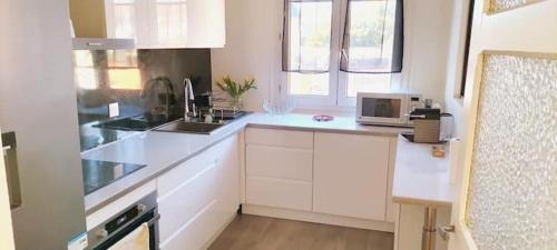 a kitchen with white cabinets and a microwave at Maison des Poules Roses in Pierrelaye
