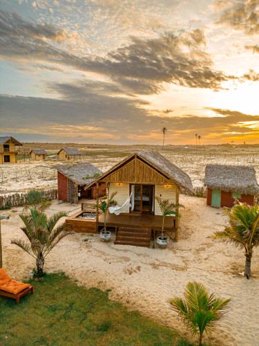 a small hut on the beach with a sunset at São Francisco Ecopousada in Guriú