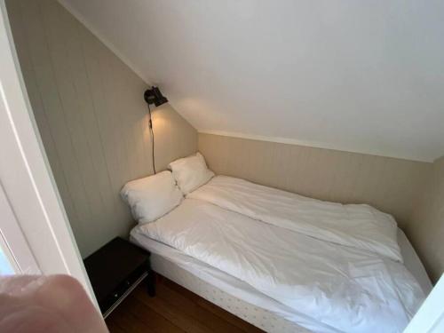 a small bed with white sheets in a small room at Modern Fisherman Cabin in Ballstad