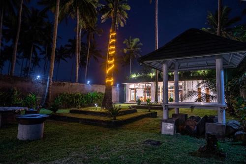 a house at night with a gazebo and palm trees at L'autentiko in Pulukan