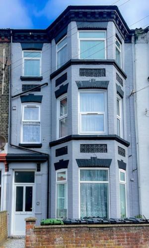 a gray house with white windows and a brick wall at Britannia Road in Great Yarmouth