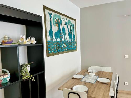 une salle à manger avec une table et un tableau au mur dans l'établissement Vénus Reims, à Reims