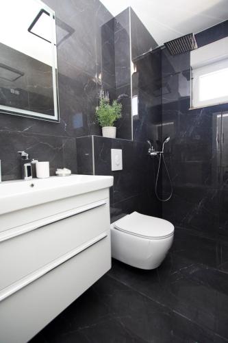 a black bathroom with a toilet and a sink at Top5 in Baška Voda