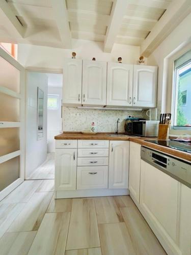 a kitchen with white cabinets and a wooden floor at Funny Füred in Balatonfüred
