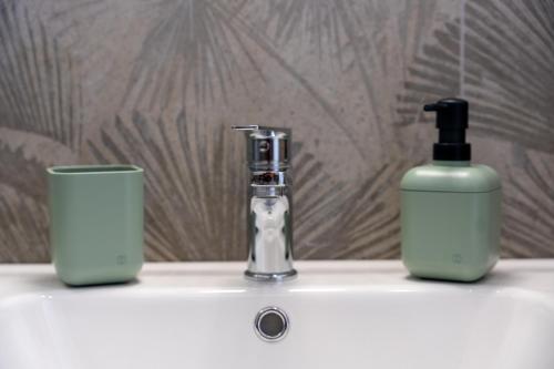 un lavandino in bagno con dispenser di sapone e bottiglia di Elegante appartamento piano terra a 200 mt dal mare a Cervia