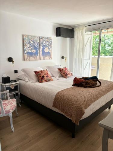 un grand lit dans une chambre avec une fenêtre dans l'établissement L'Intemporel, à Saint-Cyr-sur-Mer