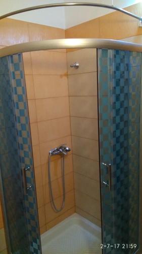 a shower with a glass door in a bathroom at El Doro Rooms in Dhërmi