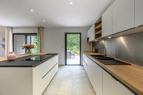 une cuisine avec des armoires blanches et des comptoirs noirs dans l'établissement La Parenthèse Nature - Belle maison à Vannes, à Vannes