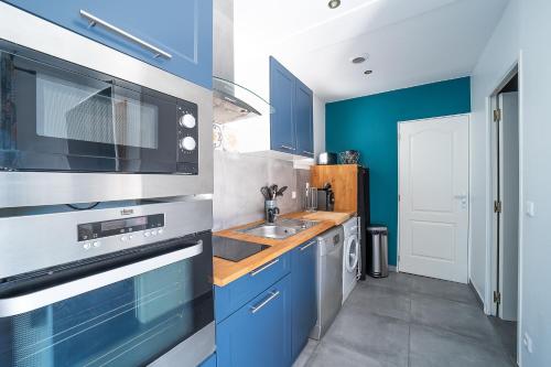 une cuisine avec des armoires bleues et un évier dans l'établissement Casa Sacha - Appt avec piscine partagée, à Fitou