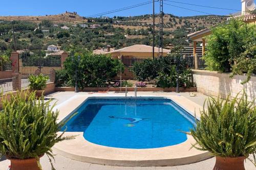 a swimming pool with two plants in front of a house at Familiar House with Private Pool and Mountains View in Venta Baja