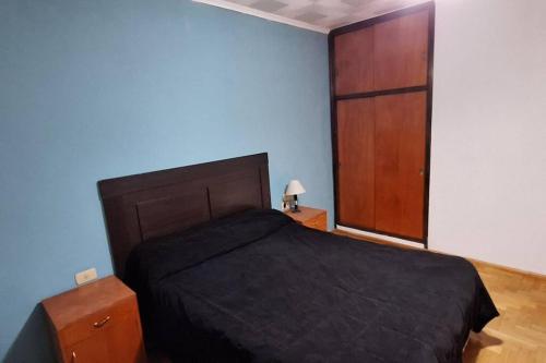 Un dormitorio con una cama negra y un armario de madera. en Alquiler Temporario FLEJj, en Santo Tomé