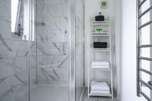 a white bathroom with a shower with white towels at The Old Flower Field in Hurstpierpoint