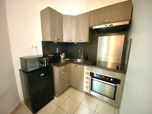 une cuisine équipée d'appareils électroménagers en acier inoxydable et d'un réfrigérateur noir. dans l'établissement Le New-York, chaleureux avec Netflix, à Limoges