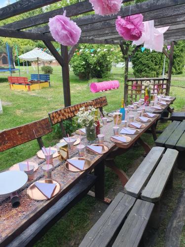 a long wooden table with plates and glasses on it at Osada Załuż in Sanok