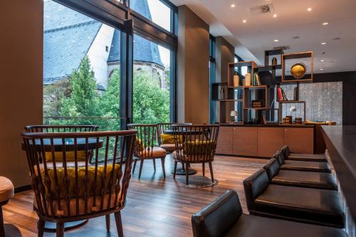 a dining room with a table and chairs and a large window at Motel One Leipzig-Augustusplatz in Leipzig