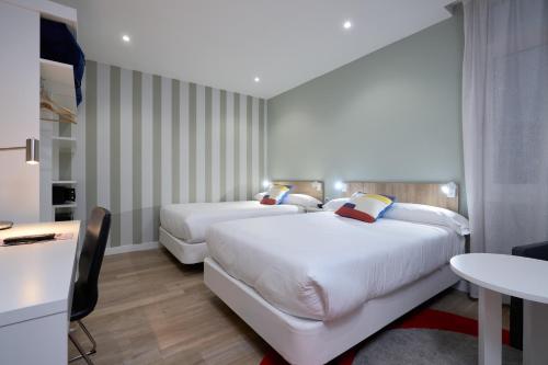 a hotel room with two beds and a table at Hotel Pasarela in Seville