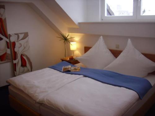 1 dormitorio con 1 cama grande con almohadas blancas y ventana en Hotel Garni Zentral en Willich