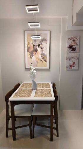 a dining room table with a white table and chairs at Sky High Suites Royal Ocean Crest Mactan in Lapu Lapu City