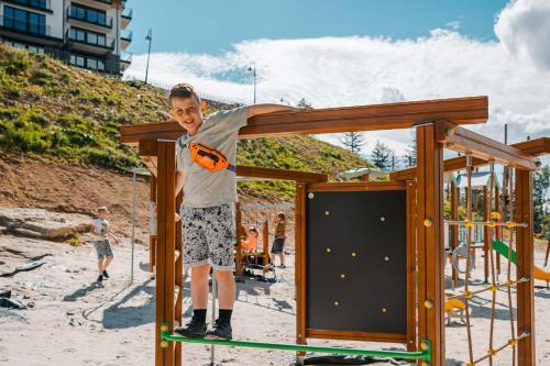 a young boy standing on a playground equipment at Kazalnica Family&Conference Resort in Karpacz