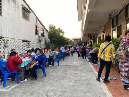 a group of people sitting at tables outside a building at โรงแรมเพิ่มพูล 1 in Nan