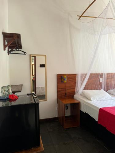 a bedroom with a bed and a tv and a mirror at Pousada Horizonte Azul in Ilha de Boipeba