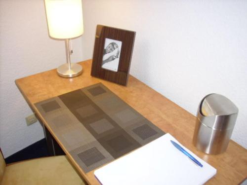 a desk with a lamp and a book on a table at Hotel Garni Zentral in Willich