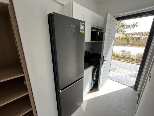 a kitchen with a stainless steel refrigerator in a room at Comfort cabin sea view & lagoon in D-bay I Beach Access Included in Dawwār Ḩājj as Sayyid Rizq