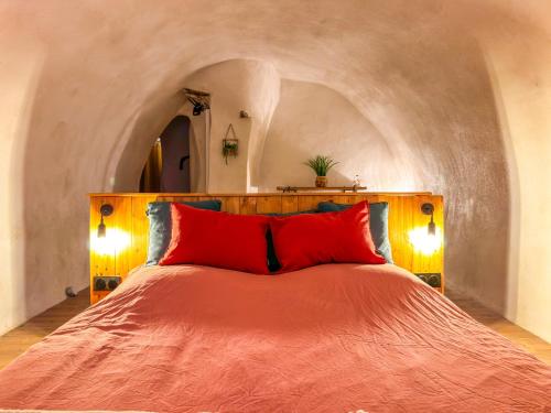 une chambre avec un grand lit avec des oreillers rouges dans l'établissement Logement entier Le Spa des Voutes Jacuzzi Cinéma, à Saint-Maximin-la-Sainte-Baume