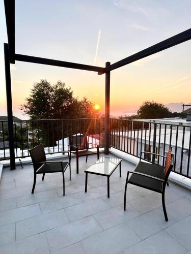 a patio with chairs and tables on a balcony with the sunset at Bungalow for 2 - Dream Oasis Dobra Voda in Dobra Voda