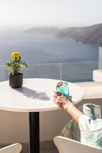 a person sitting at a white table with a plant at Rocabella Santorini Hotel & Spa in Imerovigli