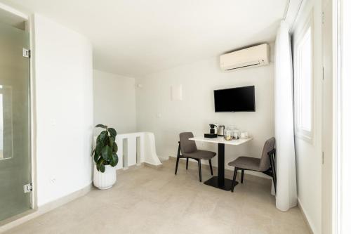 a white dining room with a table and chairs at Rocabella Santorini Hotel & Spa in Imerovigli