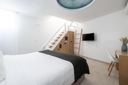 a bedroom with a bed and a ladder and a mirror at Rocabella Santorini Hotel & Spa in Imerovigli
