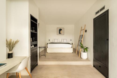 a white bedroom with a bed and a desk at Rocabella Santorini Hotel & Spa in Imerovigli