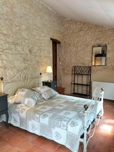 une chambre avec un lit blanc et un mur en pierre dans l'établissement Chambre d'hôtes en Dordogne proche Eymet, à Fonroque