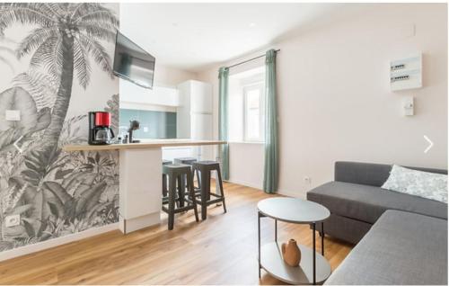 un salon avec un canapé et une cuisine avec une fresque de palmier dans l'établissement Appartement Modulable, à Arras