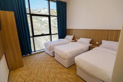 a hotel room with three beds and a window at فندق ديار الكرم1 - diyar alkaram1 in Makkah