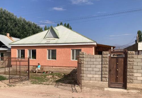 a house with a person sitting in front of it at Gulnara guesthouse in Kochkorka