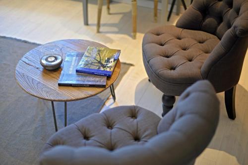 a coffee table with a book and a clock and two chairs at La Couette de l'Ours in Aywaille