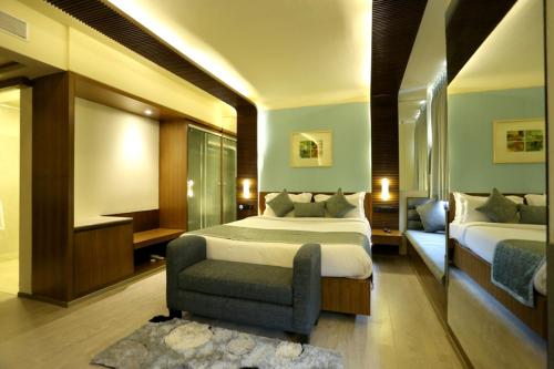 a hotel room with two beds and a chair at Regenta Orkos Kolkata by Royal Orchid Hotels Limited in Kolkata