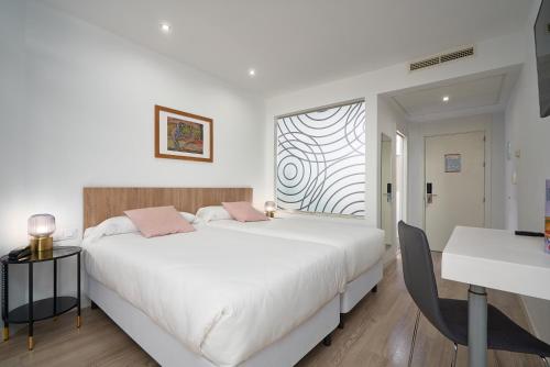 a white bedroom with a large bed and a window at Hotel Pasarela in Seville