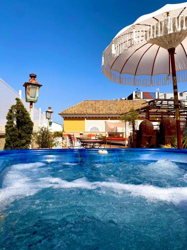 a large swimming pool with an umbrella and a house at Alcoba del Rey de Sevilla in Seville