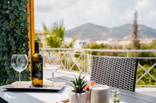 a bottle of wine sitting on a table with two glasses at Athena & Phevos Luxury Suite With View In Nea Makri in Nea Makri