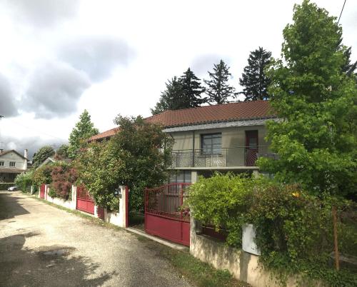 a house with a red fence next to a street at Le Passage Meublé de tourisme Trois Etoiles 1 à 6 voyageurs in Châtillon-sur-Chalaronne
