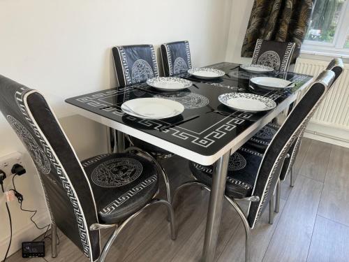 a black dining room table with black and white chairs at 3-Bedroom Cosy Reading House in Reading