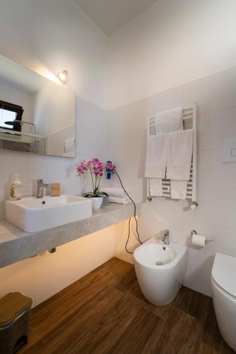 a white bathroom with two sinks and a toilet at Hotel Antica Cascina Del Golfo in Scopello