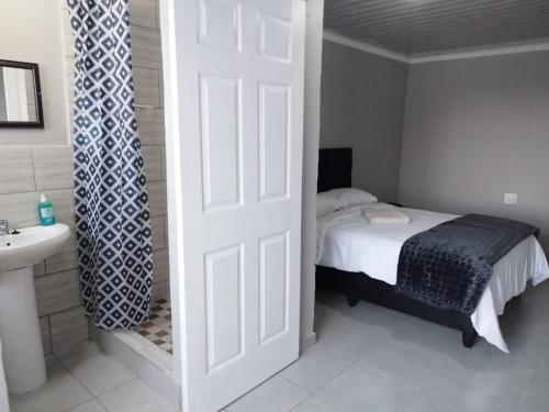 a bedroom with a bed and a sink and a door at Rivoni Guest House in Soweto
