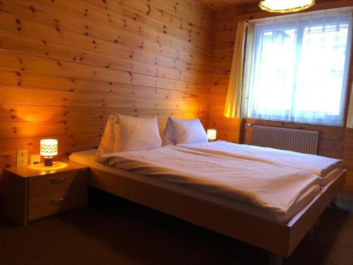a bedroom with a bed with a wooden wall at Hotel Gebidem in Visperterminen